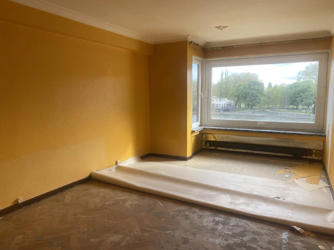 Pièce aux murs jaunes avant les travaux de finitions intérieures à Liège centre, au 5e étage